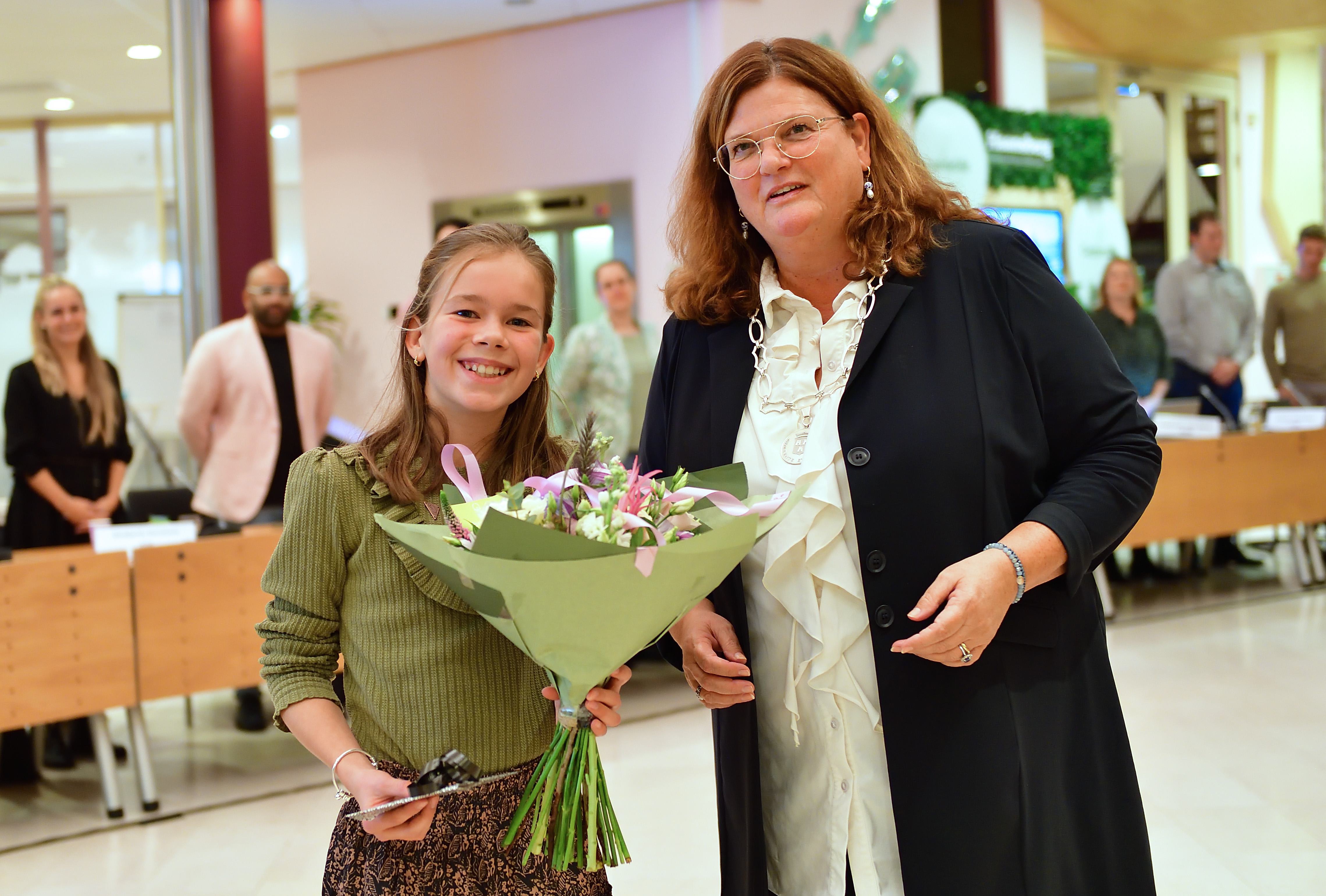 Burgemeester Marina Starmans geeft de nieuwe jeugdburgemeester Vieve van Kuijk een boeket bloemen
