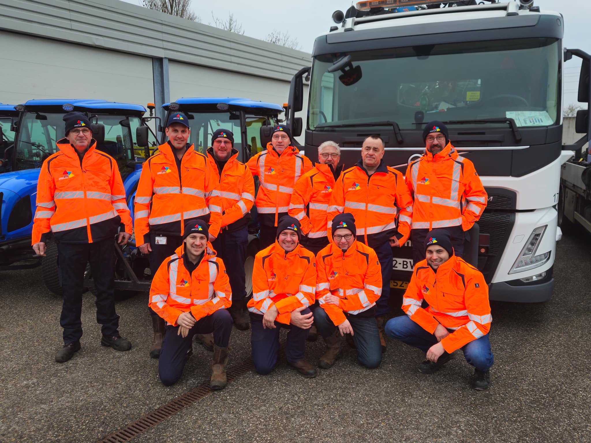 Groepsfoto van de gladheidsbestrijders van Gemeente Etten-Leur met op de achtergrond enkele wagens voor het strooien van zout