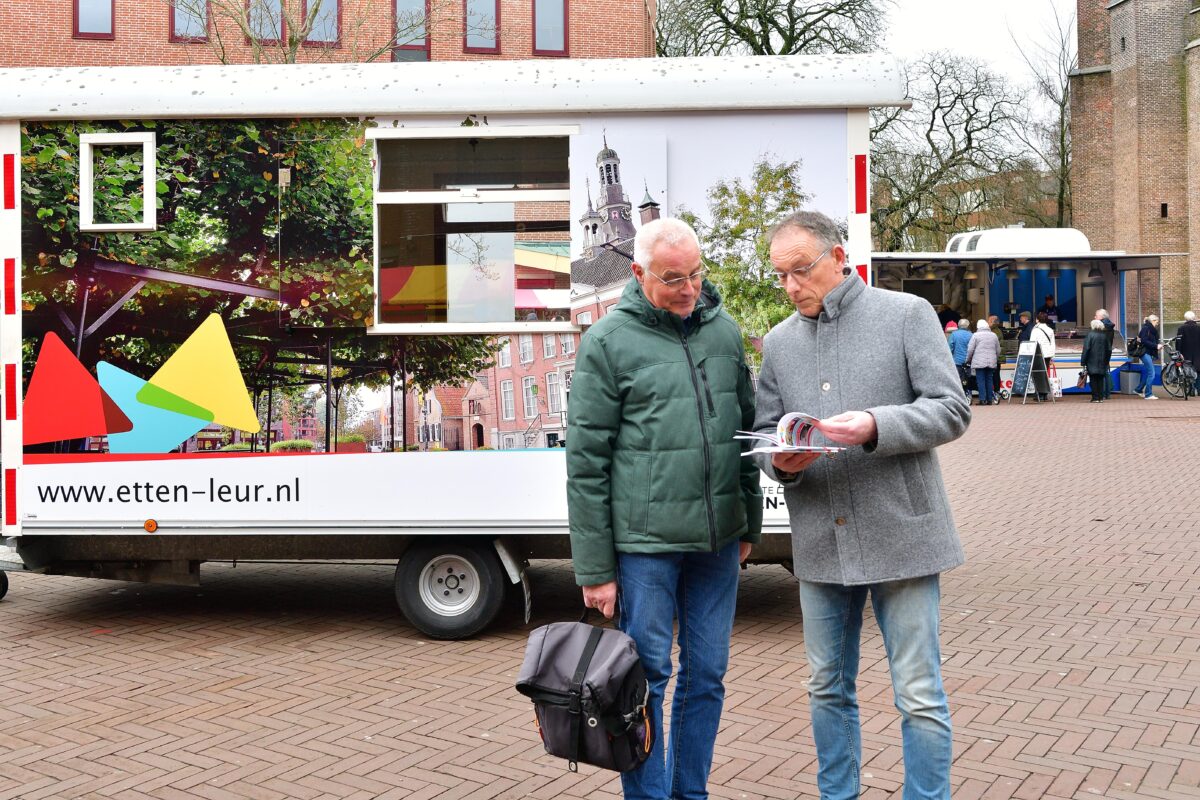 Wethouder René Verwijmeren reikt op de weekmarkt het boekje ‘Doe mee in Etten-Leur’ uit aan senioren